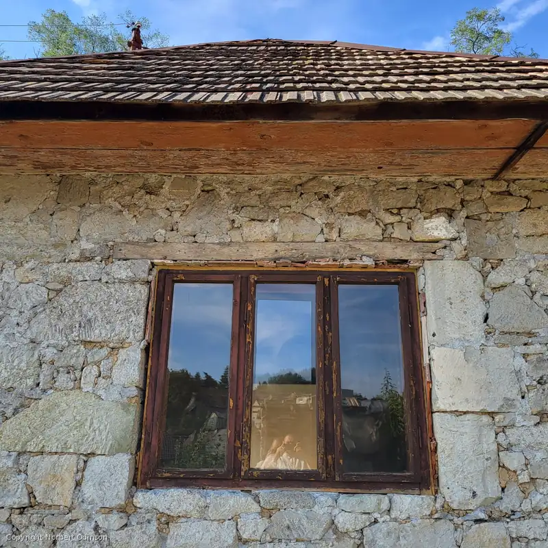 Kamenná fasáda s oknom pod drevenou strechou